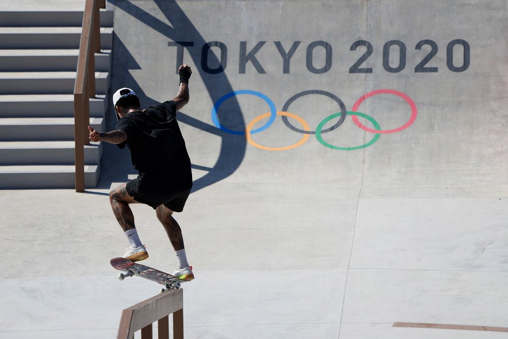 Photo taken from behind of Nyjah Huston, of the United States, training during a street skateboarding practice session at the 2020 Summer Olympics, Wednesday, July 21, 2021, in Tokyo, Japan. He wears black and a white hat, and rides along a rail.