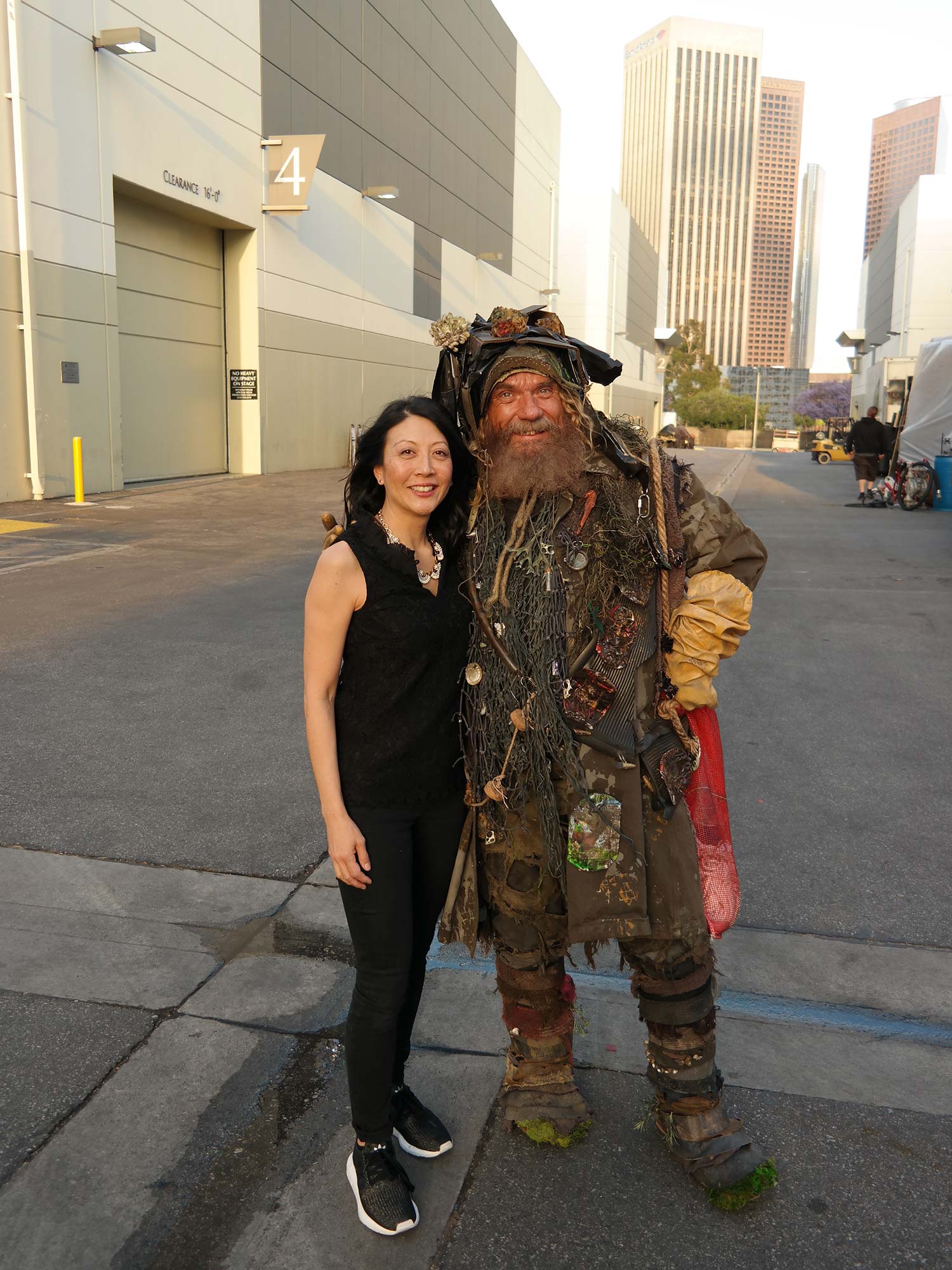 Costume designer Joyce Kim Lee (CFA’93) on the Los Angeles Center Studios backlot in downtown Los Angeles prepandemic, with one of her costumes for Disney Channel’s Just Roll with It, worn by actor Christian Calloway as “Garbage Pete.” Pete is dressed like a pirate and has little bits of things attached to him.