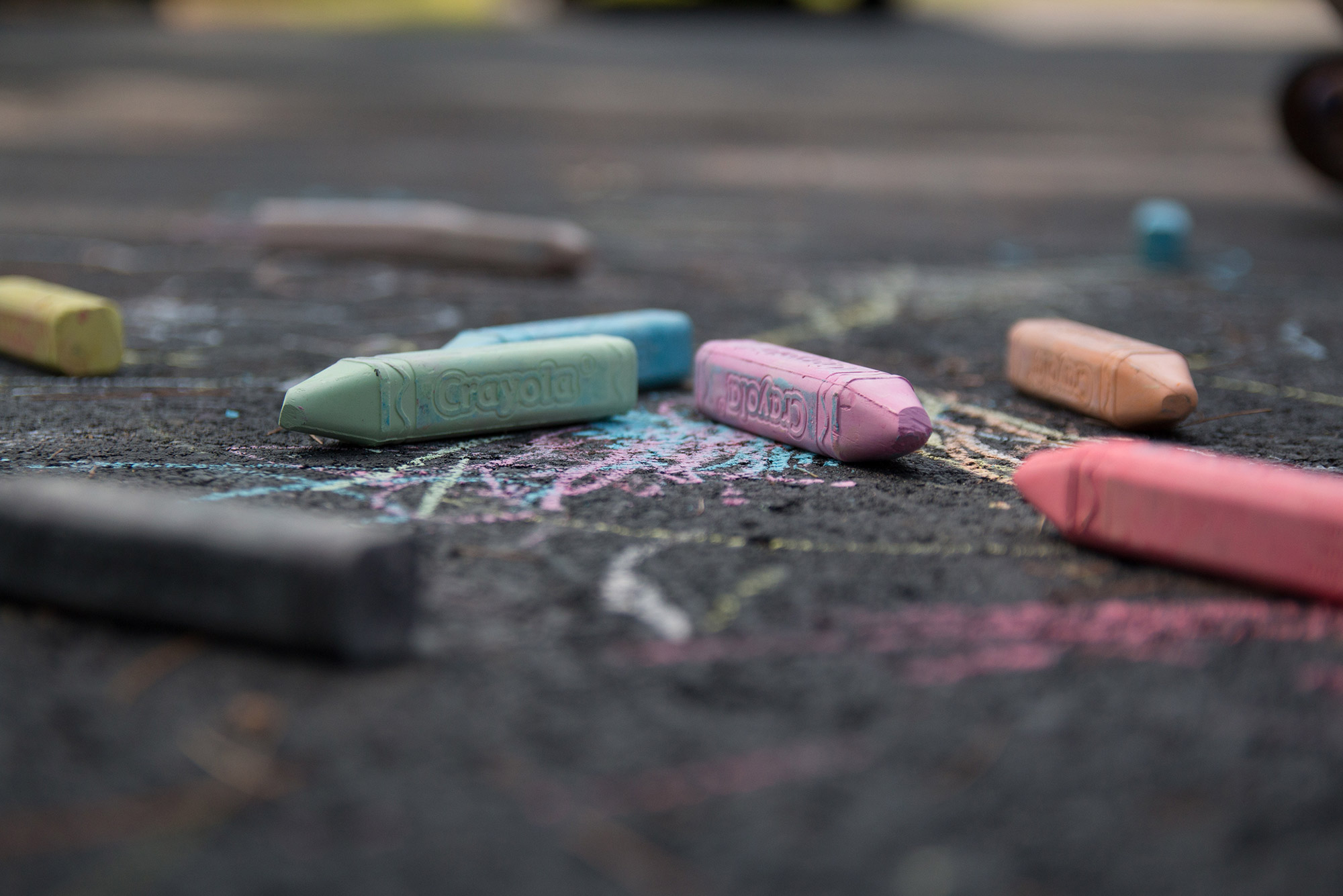 Photo of crayola sidewalk chalk pieces of various pastel colors laying on pavement.