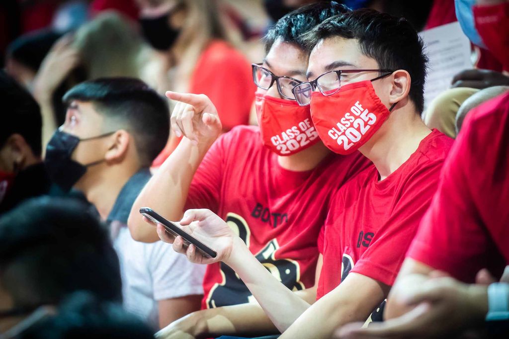 Two members of the Boston University Class of 2025 who look like twins react during the Matriculation ceremony at Agganis Arena.