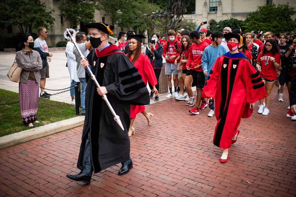 A man carrying a scepter and two student leaders lead the Matriculation Walk of the Boston University Class of 2025