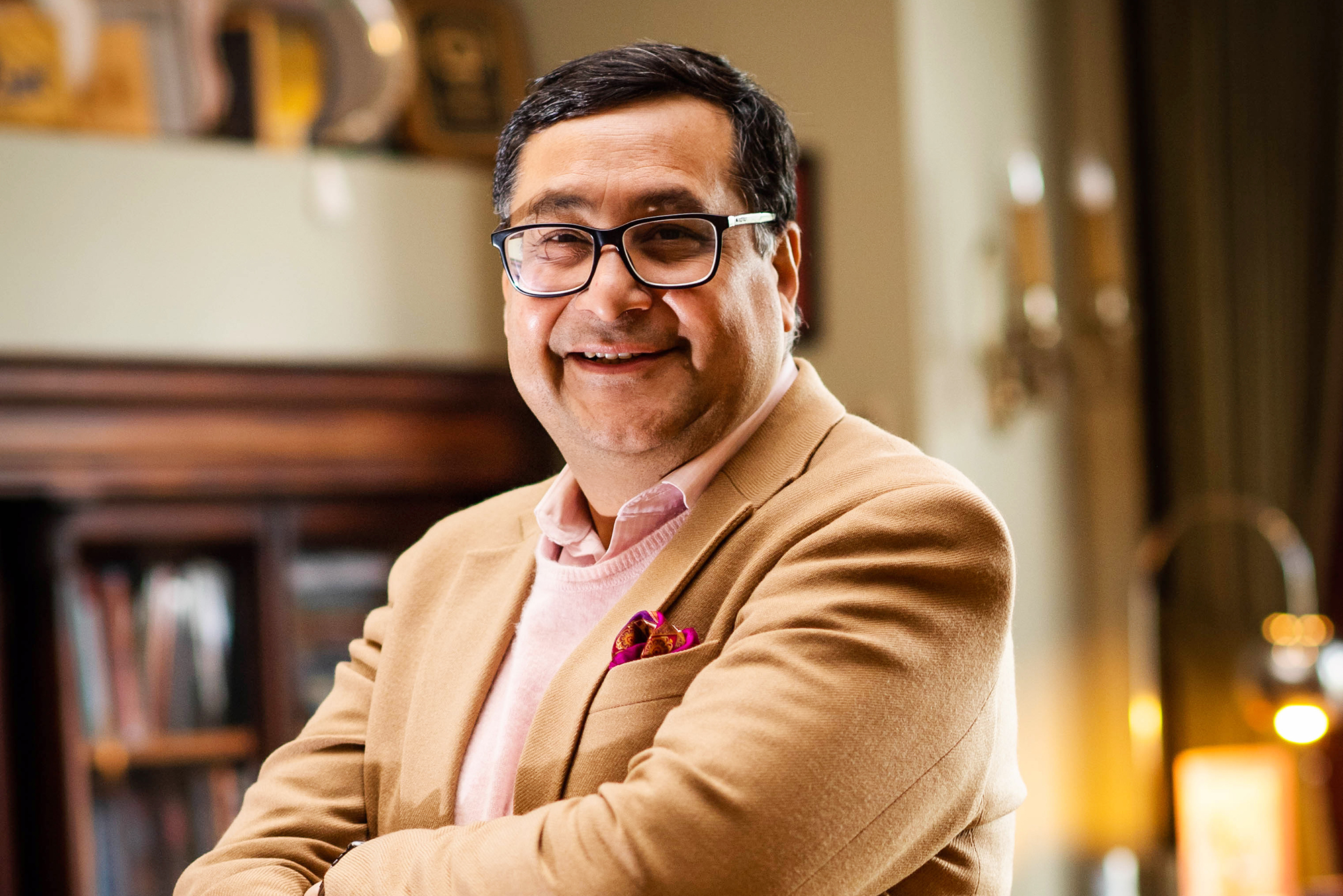 Dean of BU’s Pardee School of Global Studies, Adil Najam, smiles and poses with arms crossed for a photo in his office