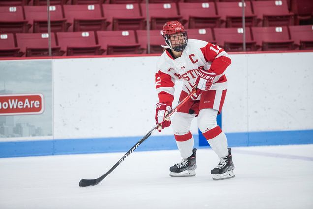 female ice hockey player holding stick at the ready for oncoming puck