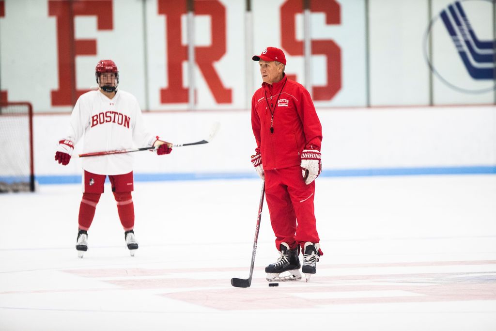 Head coach of the women’s hockey team, Brian Durocher, skates with a stick and puck as he leads a practice on the ice.