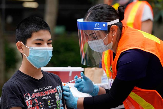 A 13 year-old boy gets a shot of the Pfizer COVID-19 vaccine at the First Baptist Church of Pasadena in New York.