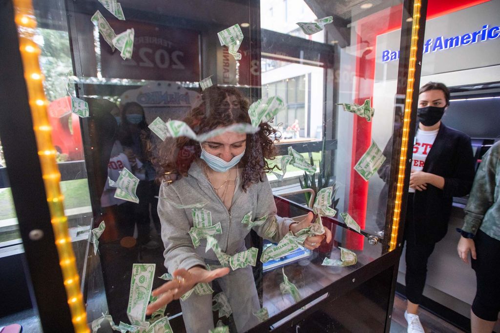 A student scrambles to grab as many fake dollar bills as possible in twenty seconds during the First Day Festival September 2 at George Sherman Union. Every bill caught was worth one dining point, and she managed to grab 10. The game was hosted by BU Dining Services. At right is BU Dining Services marketing manager Laurel O’Keefe.