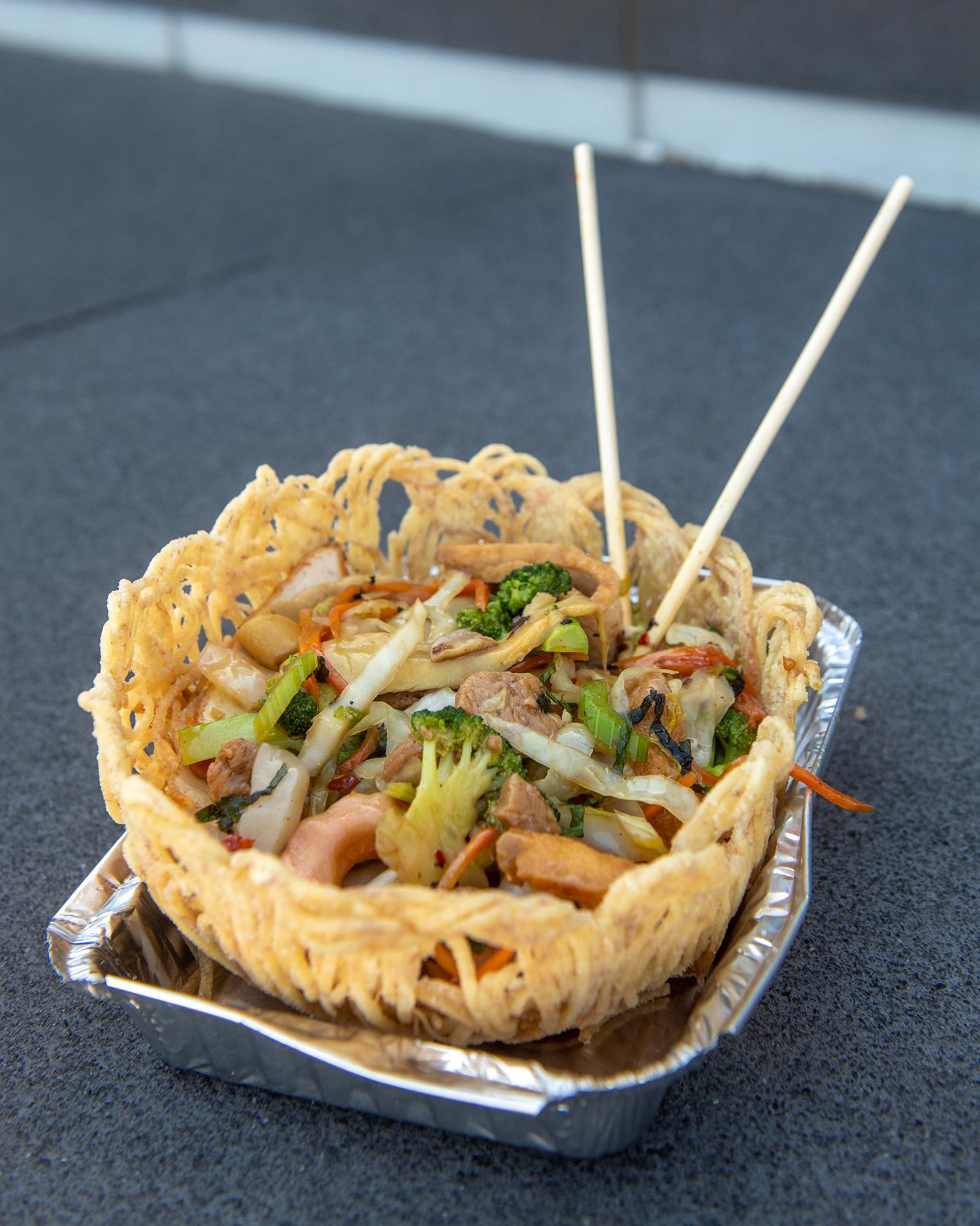 Photo of the Crispy Taro Nest from Grasshoppers on N Beacon St, Allston, Marsh 23. Strands of crispy taro form a bowl shape that holds a noodle salad with broccoli, onions and other vegetables.