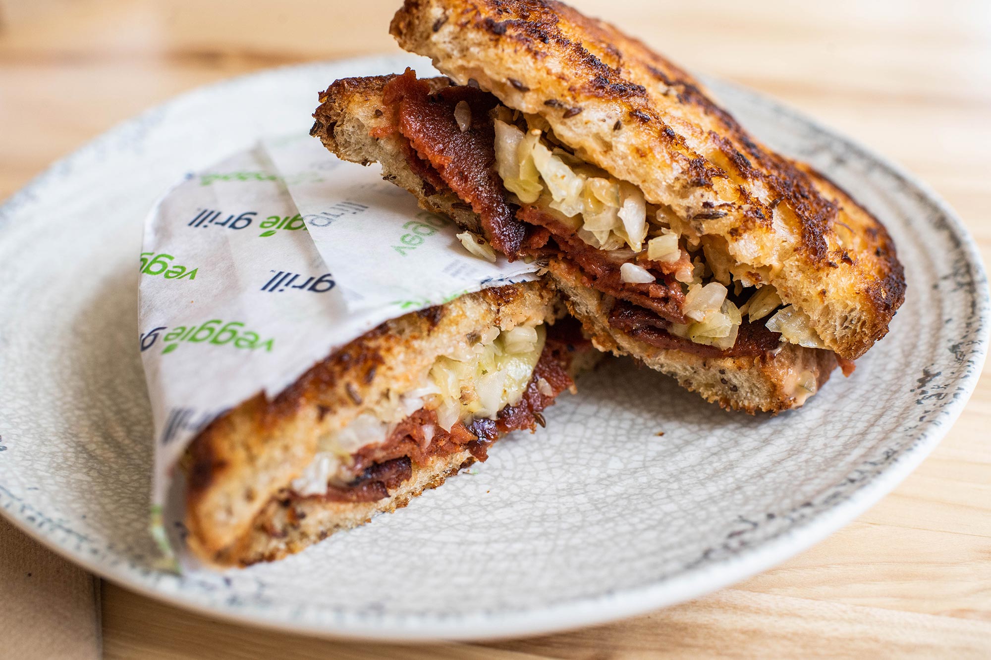 Photo of Rueben on Rye at Veggie Grill in Harvard Square. The sandwich is crispy on the outside, and one piece is wrapped in paper.