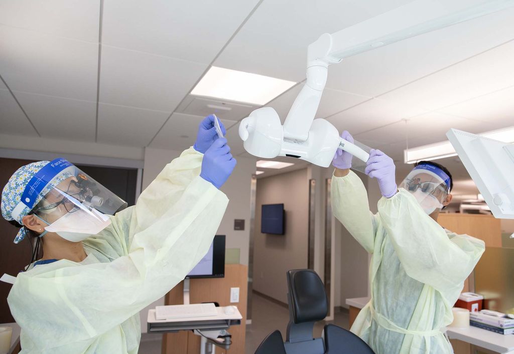 Boston University dental students, Manavi Nagai and Benson Delos Reyes, prepare one of the new patient treatment rooms for use.