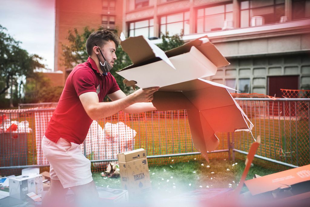 Resident Sustainability leader, Matt Tate (CAS 22) breaks down boxes outside of west campus during move-in on Saturday, August 28, 2021. In foreground, a red hazy border is seen around him.