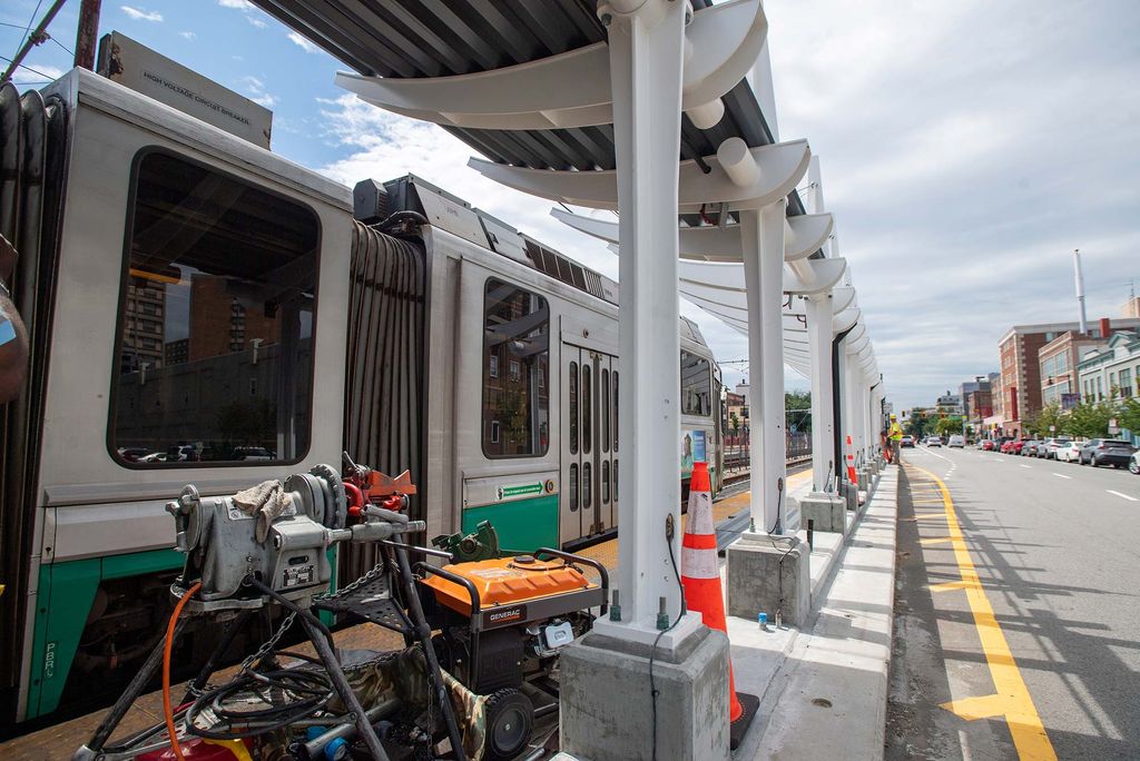 Photo of a Generac machine at the Babcock Street T stop on August 18. A green line car is passing by the platform, and Comm Ave is seen at right.