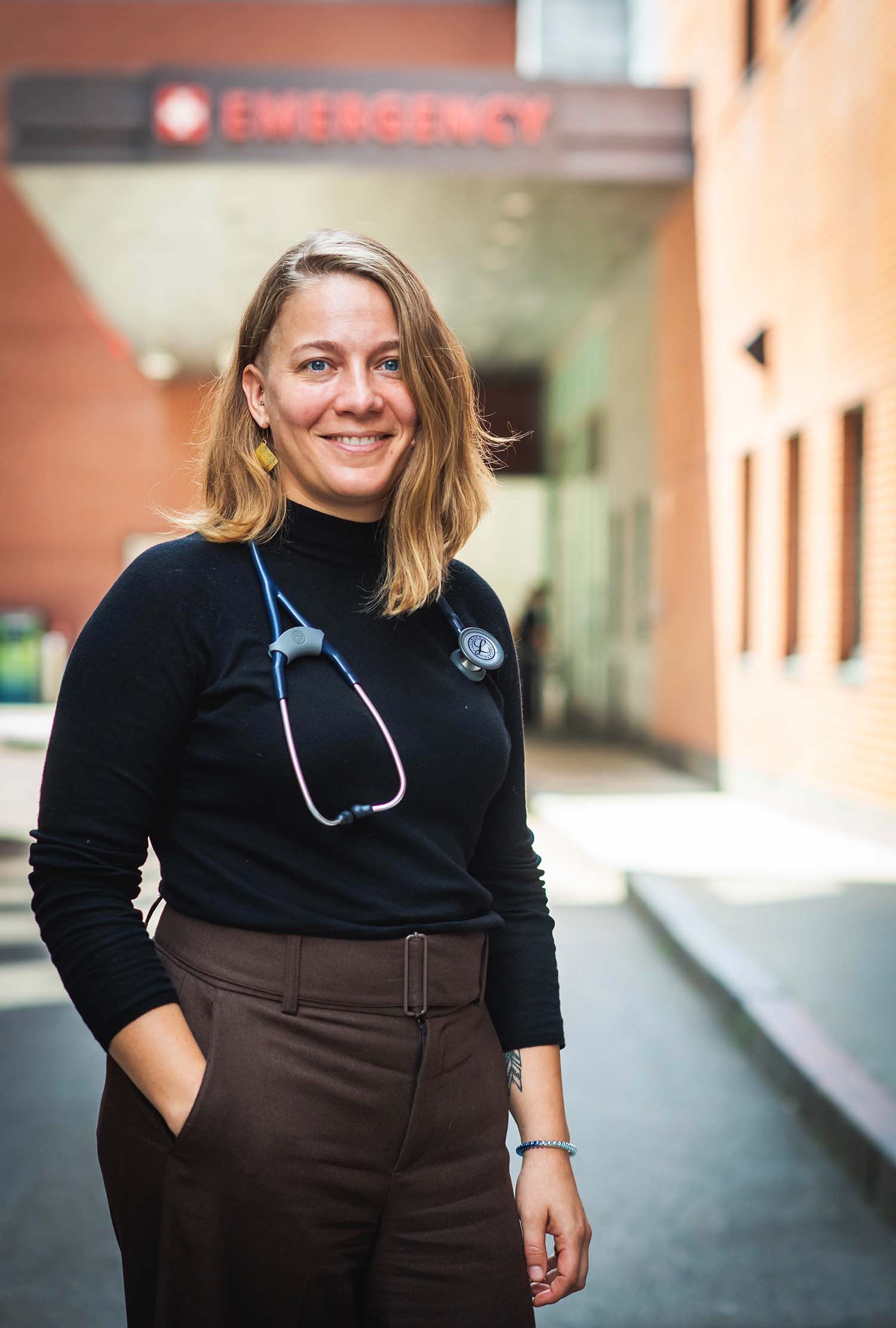 Portrait of Dr. Sarah Kimball, directory of the Boston Medical Center Immigrant and Refugee Health Center, standing outside of the BMC Emergency Room entrance.