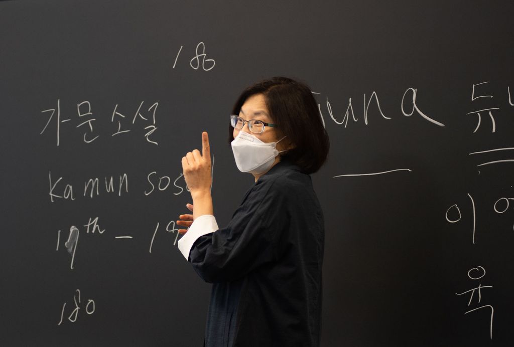 Associate professor Yoon Sun Yang, wearing a face covering, teaches Major Authors in Korean Literature class, September 2 at Boston University College of Arts and Sciences. Writing is on a chalk board behind her.