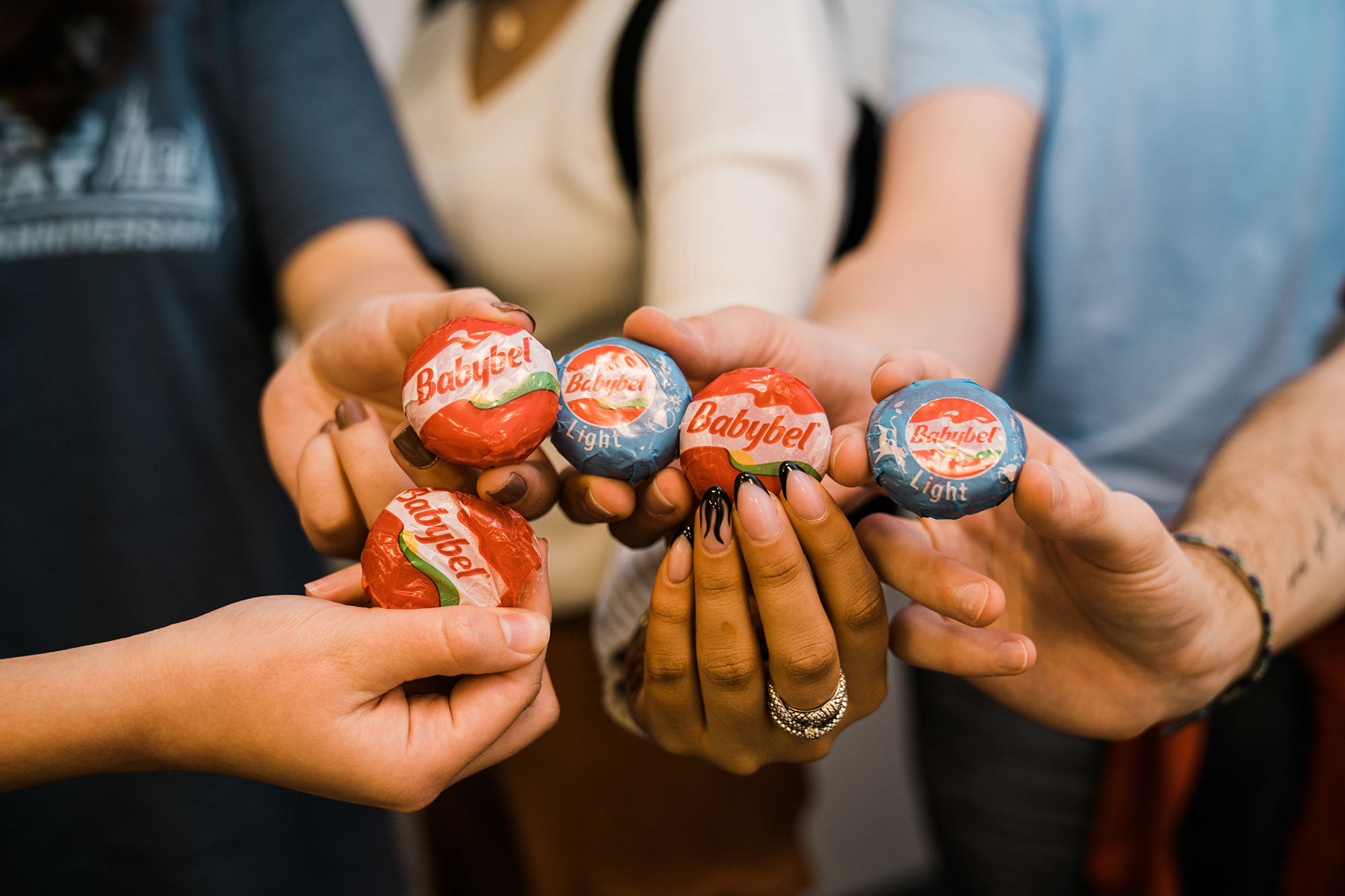 photo of the hands of BU's Cheese Lovers Society holding up a variety of Babybel cheeses together for the camera.