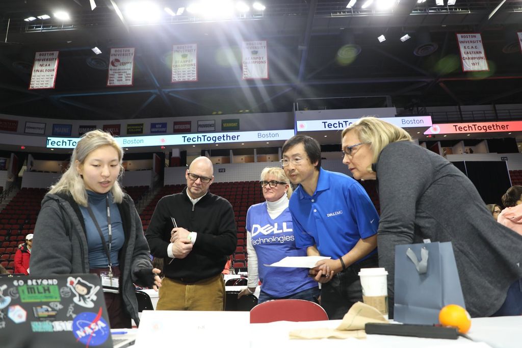 Photo of a young woman with blonde hair presenting her work to folks from Dell at TechTogether Boston 2019-2020.