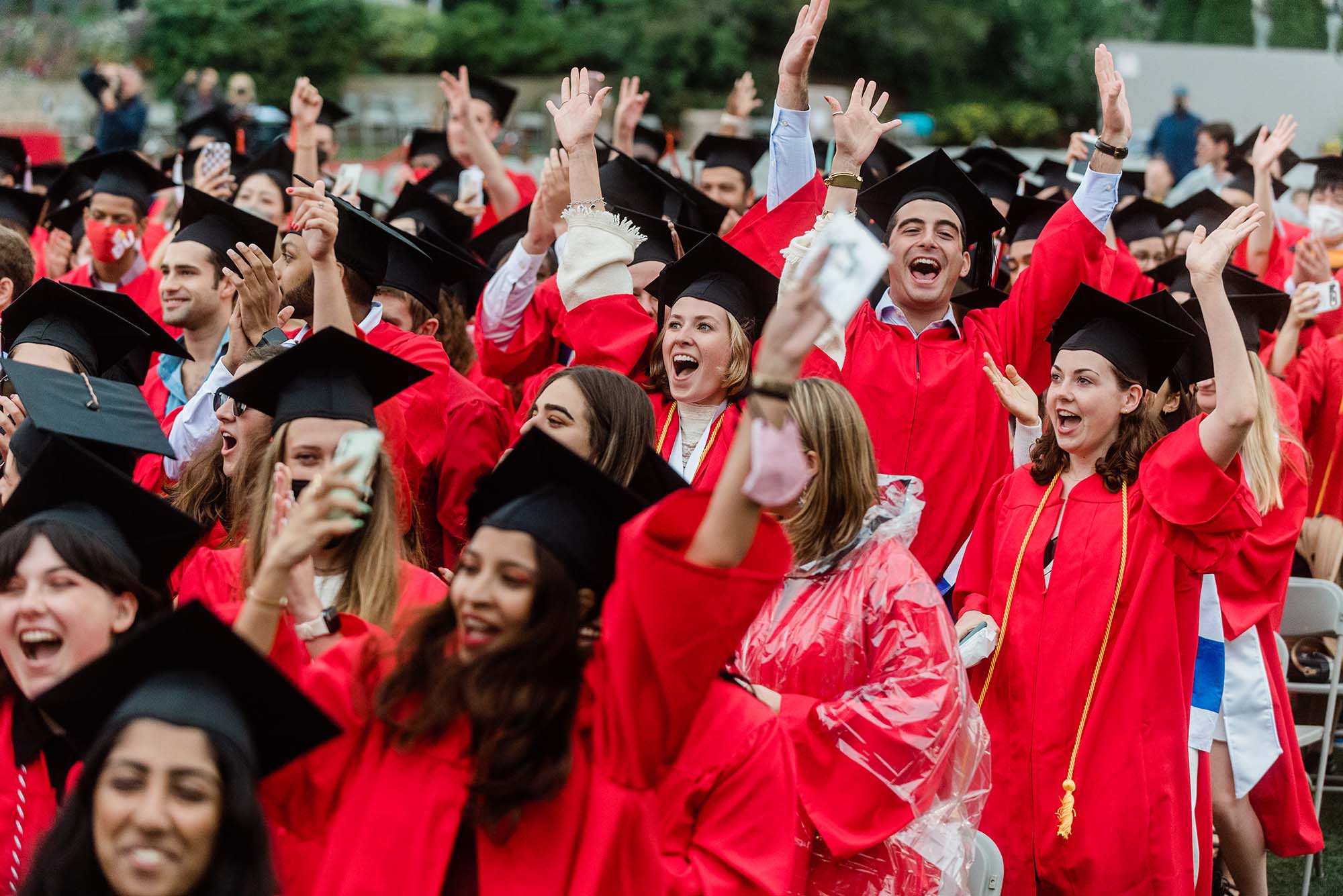 Photo of a crowd of students raising their arms and celebrating at commencement.