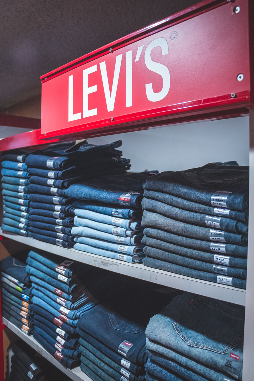 jeans folded neatly on metal shelves as a large, red 'Levi's' sign hangs above them