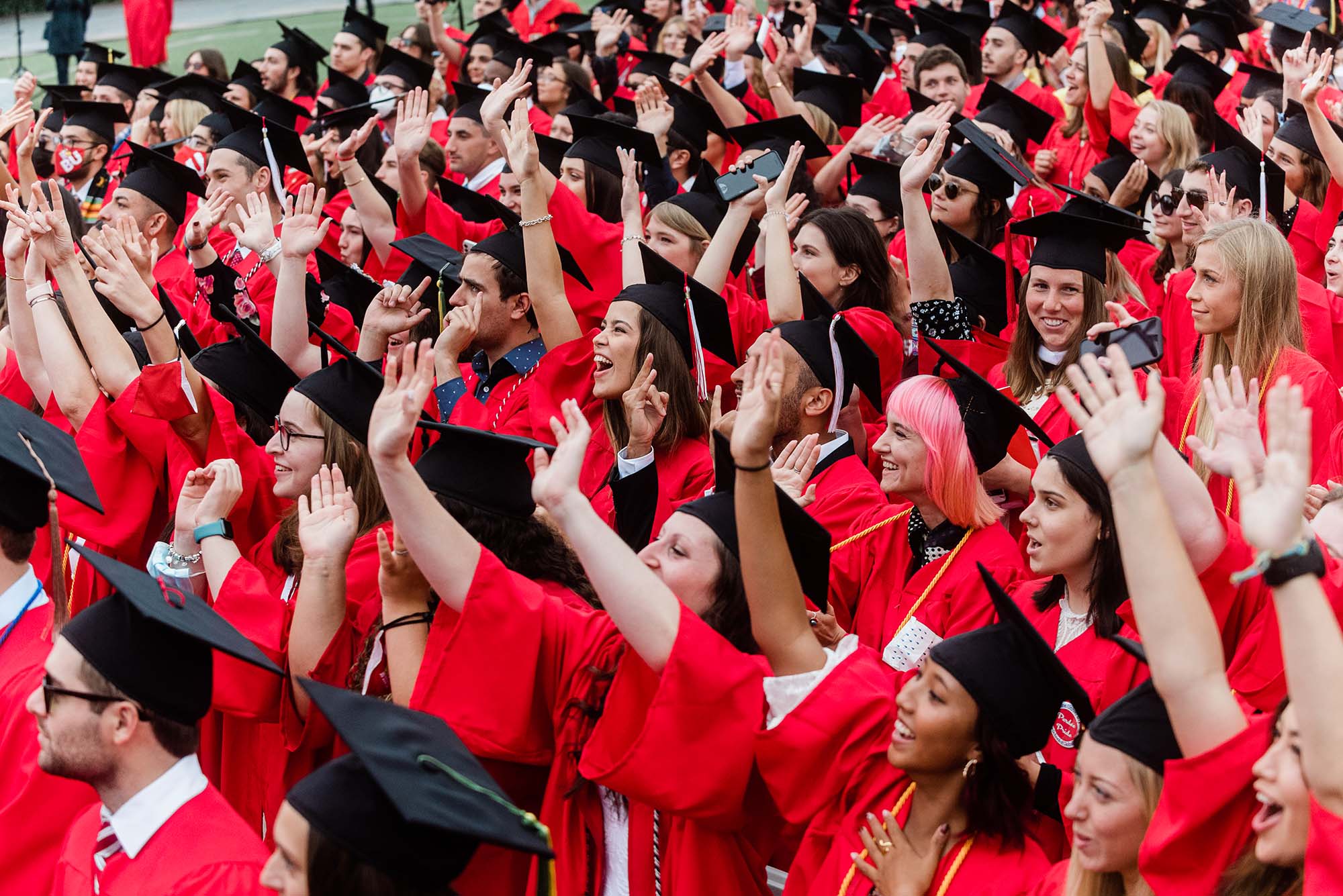 Photo of a crowd of students raising their arms and celebrating at commencement.