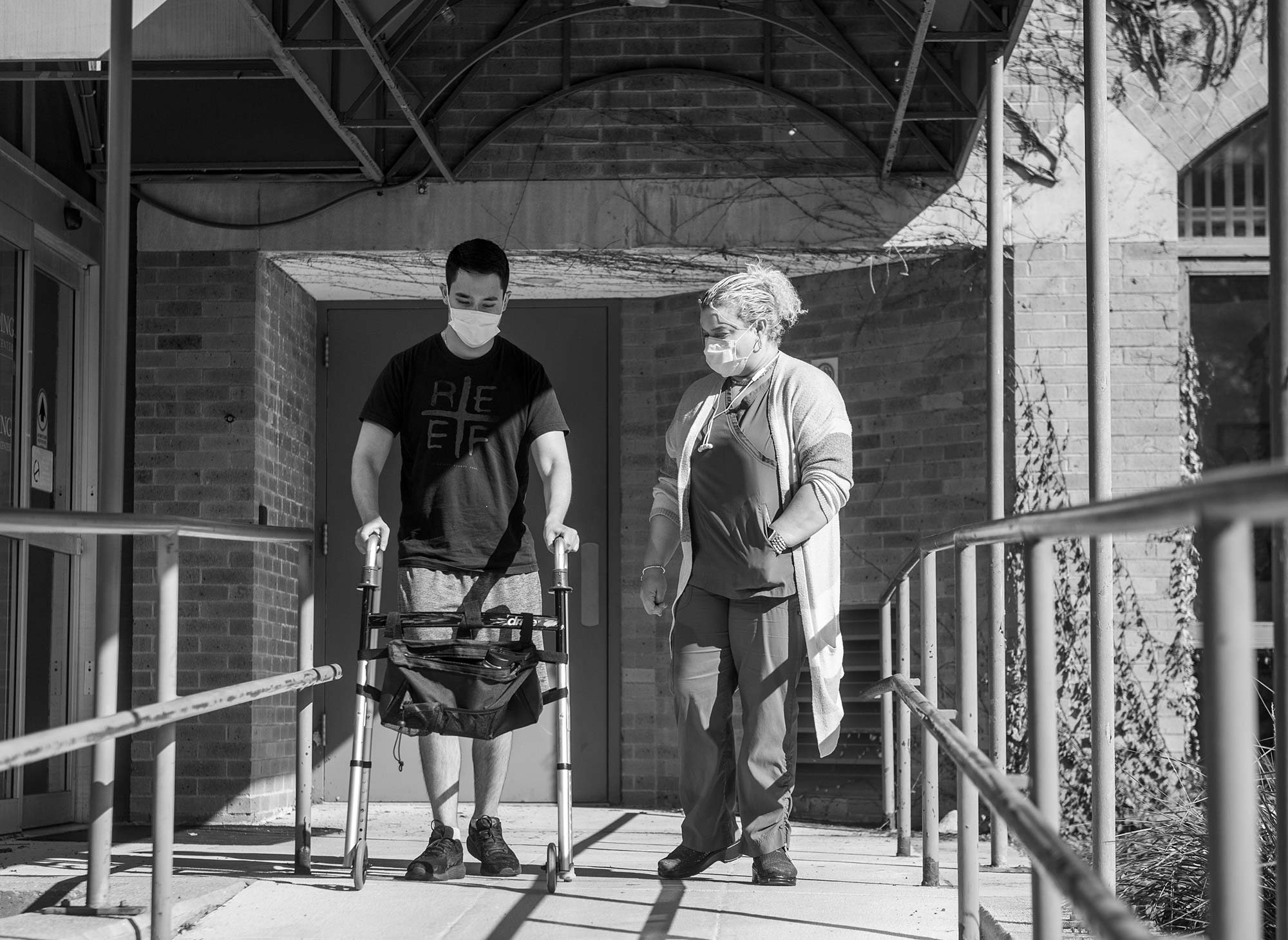 Black and white Photo of Ethan Wang on a lufthansa flight in an emergency Patient Transport unit. He lays down on a stretcher, and there are lots of wires and medical equipment around him.