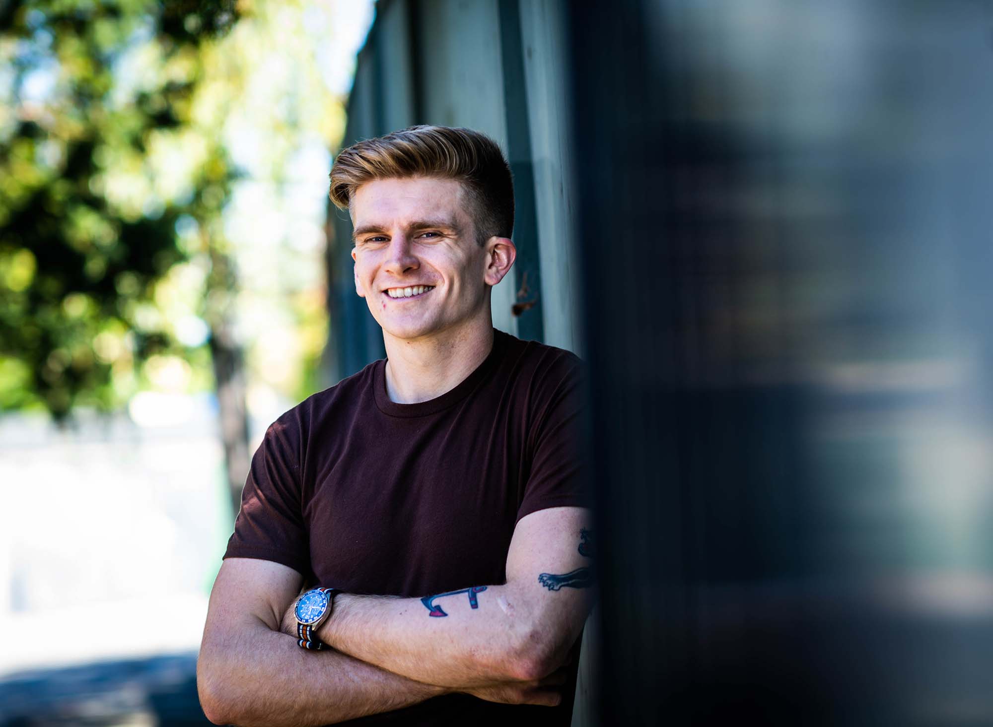 Portrait of Macken Murphy leaning against a wall with arms crossed.