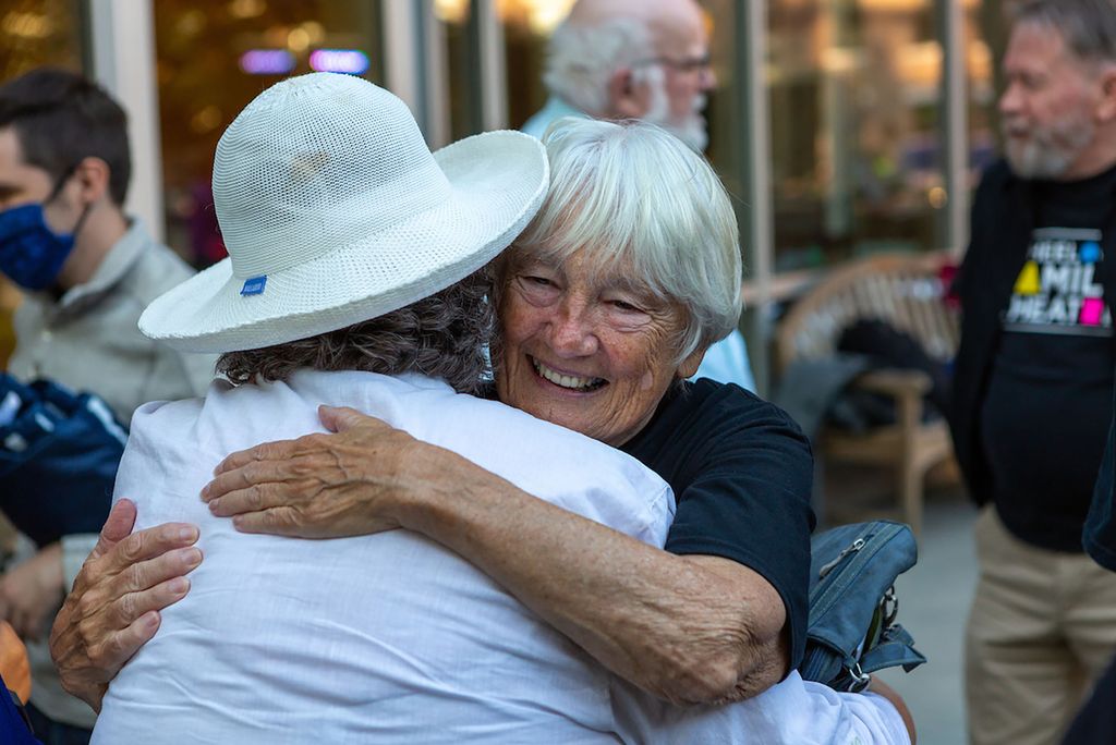 Photo of Jane Stabb (WFT Founder) hugging another alumn. She smiles wide and has white hair.