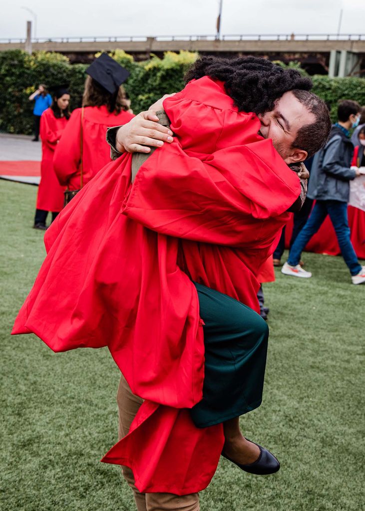 Two students embrace in a big hug following Boston University's graduation for the Class of 2020. One student has jumped up into the other's arms.