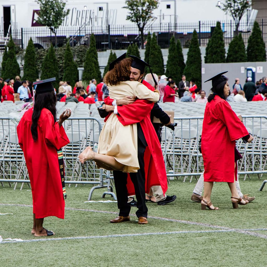 Two students embrace in a celebratory hug after Boston University's Class of 2020 graduation.