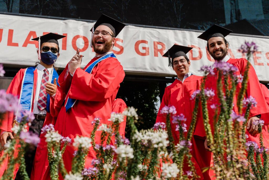 Four Class of 2020 students stop to pose for a photo as they walk onto Nickers Field for Boston University's 147th Commencement ceremony.