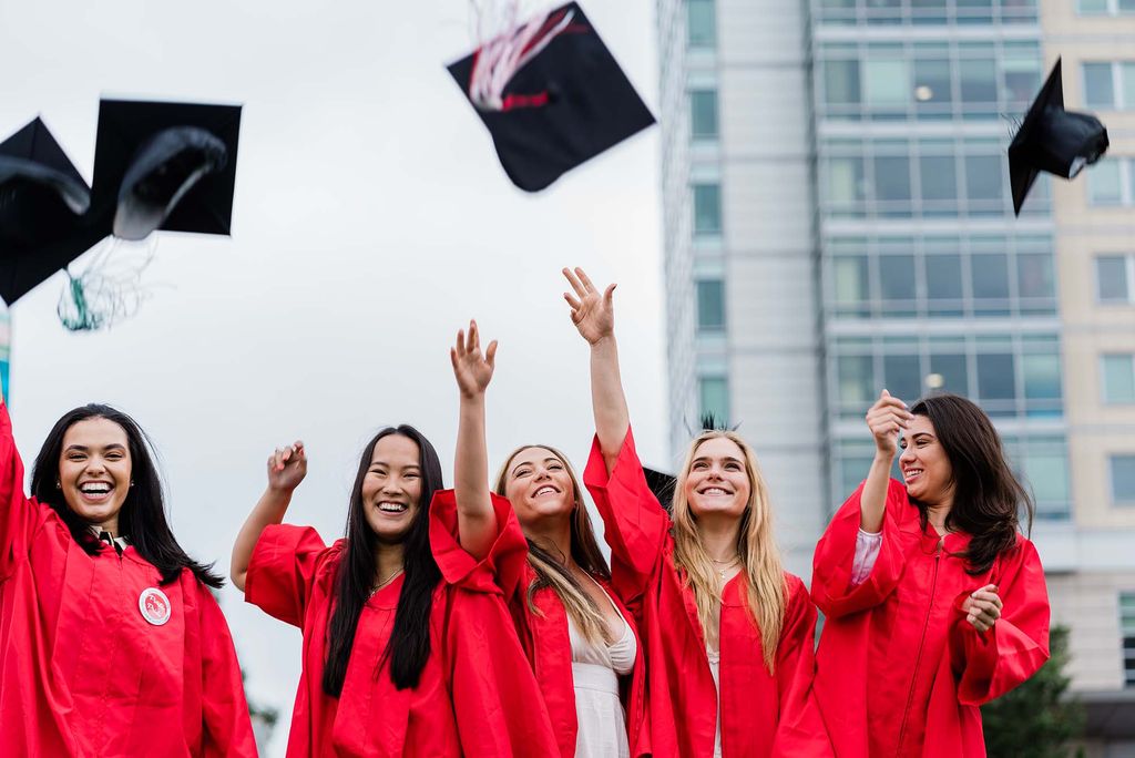 Five Class of 2020 graduates throw their graduation caps in the air on Nickerson Field following Commencment.