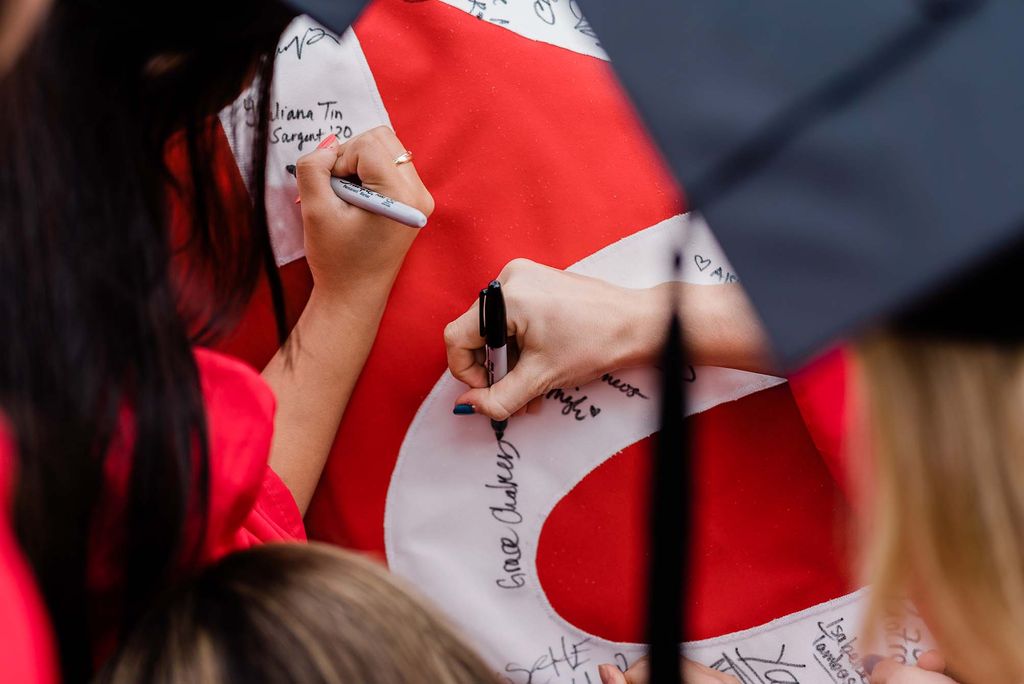 BU Class of 2020 graduates sign the Class of 2020 banner.