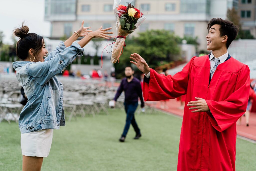A friend or family member throws a bouquet of flowers to a BU Class of 2020 graduate.