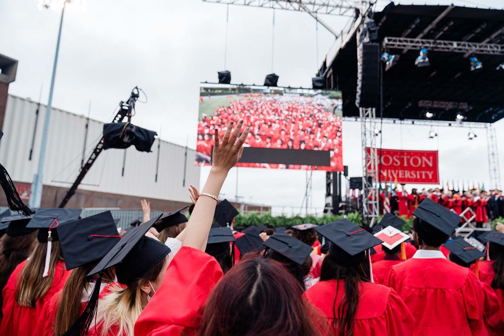 Graduating students cheer as they are projected on a big screen to the left of the stage suring Commencement.