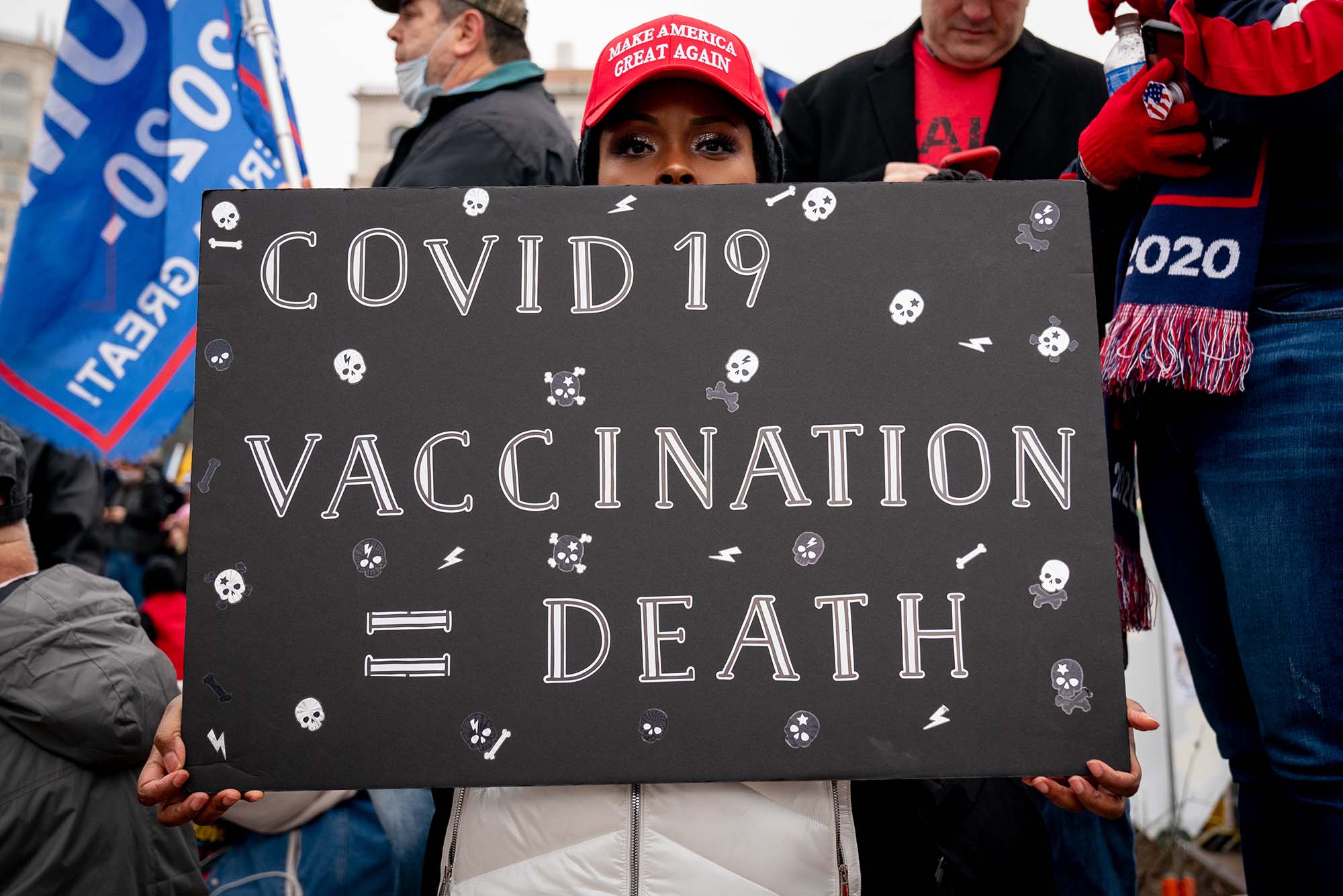 A protester holds a sign that says 'COVID 19 Vaccination = Death'