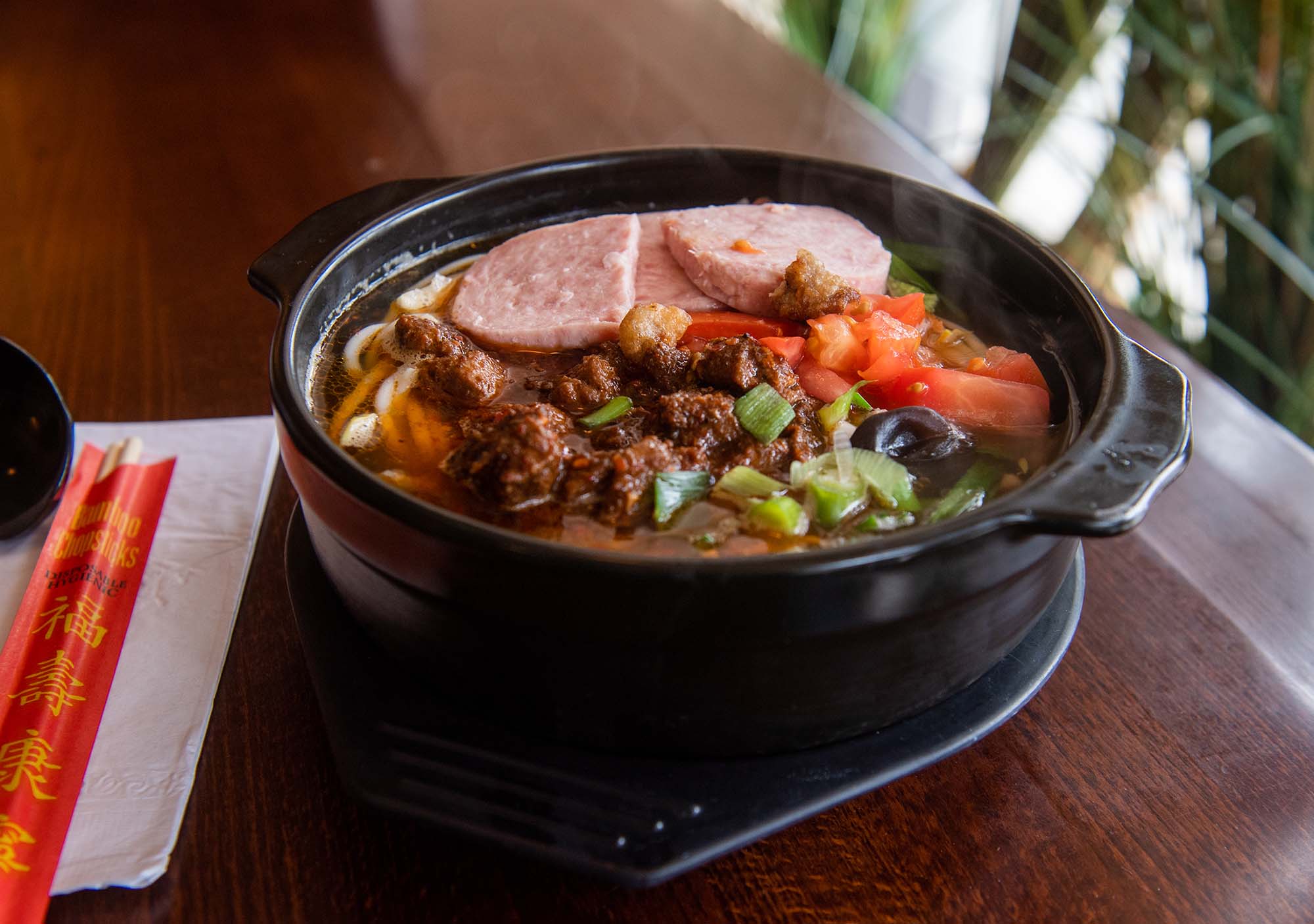 photo of a steaming Rice Noodle Soup in Clay Pot at South of the Clouds in Brighton. Soup piled high with mushroom, quail egg, chicken, pork tenderloin, tofu skin, bean sprouts, and more.