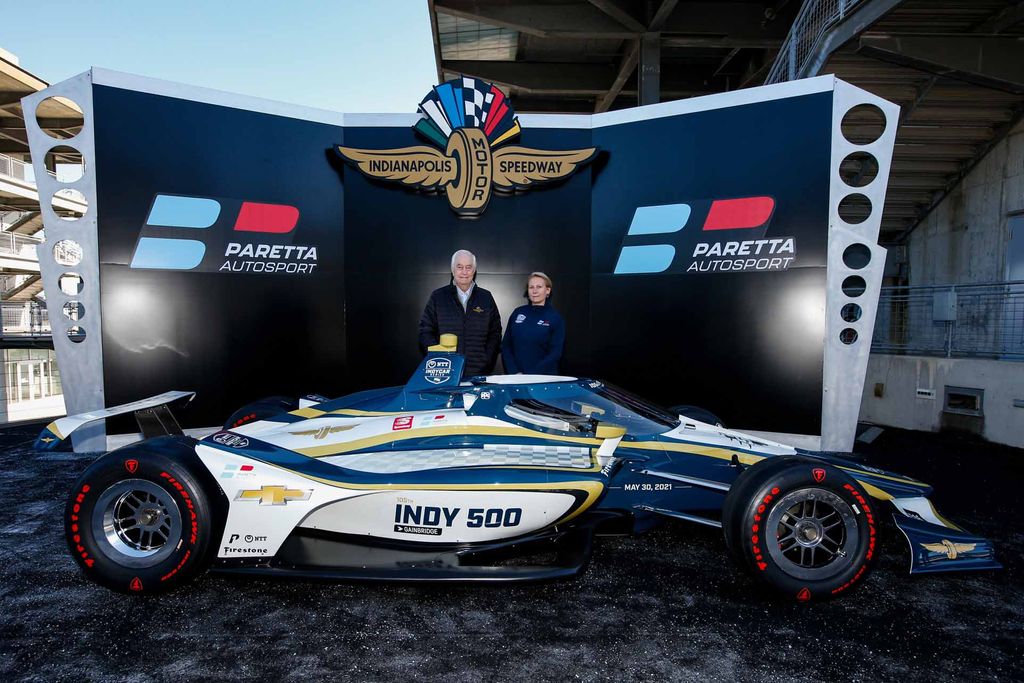 Roger Penske and Beth Paretta pose for a photo behind a show IndyCar during the announcement about the formatio of the Paretta Autosport female indycar team.