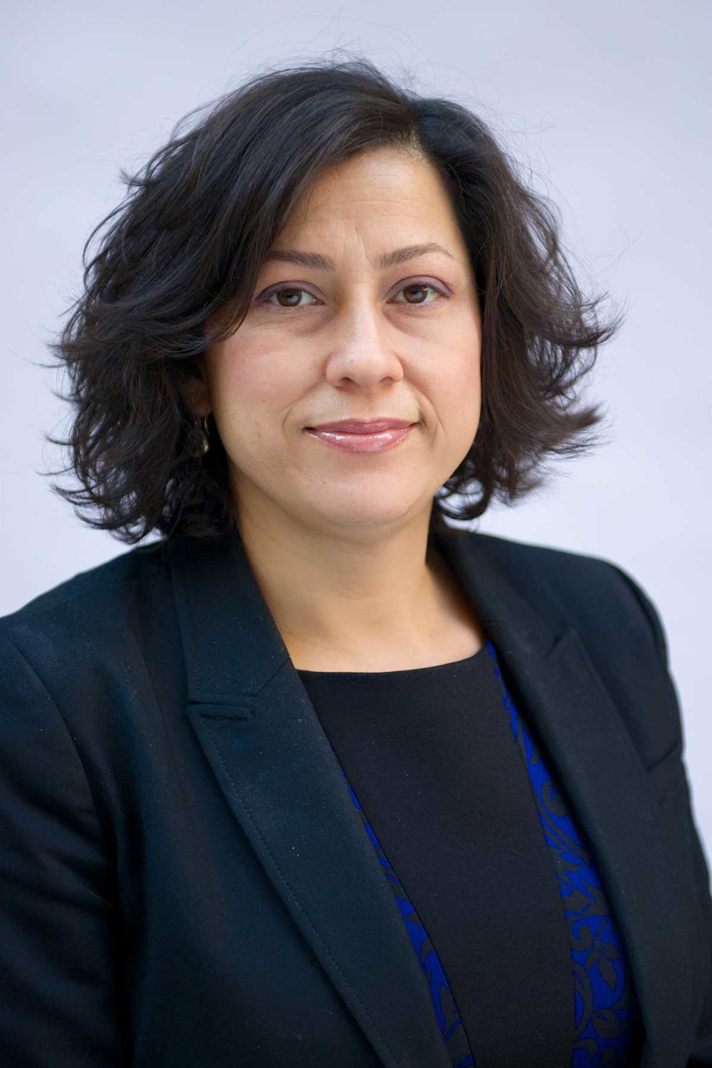 Headshot of Alexandra Oliver-Dávila, Executive Director. She wears a dark blue blazer, has short brown hair and slightly smiles.