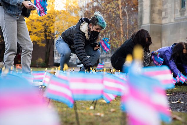 Kaiden Kane places flags on Alpert Mall for Transgender Day of Remembrance