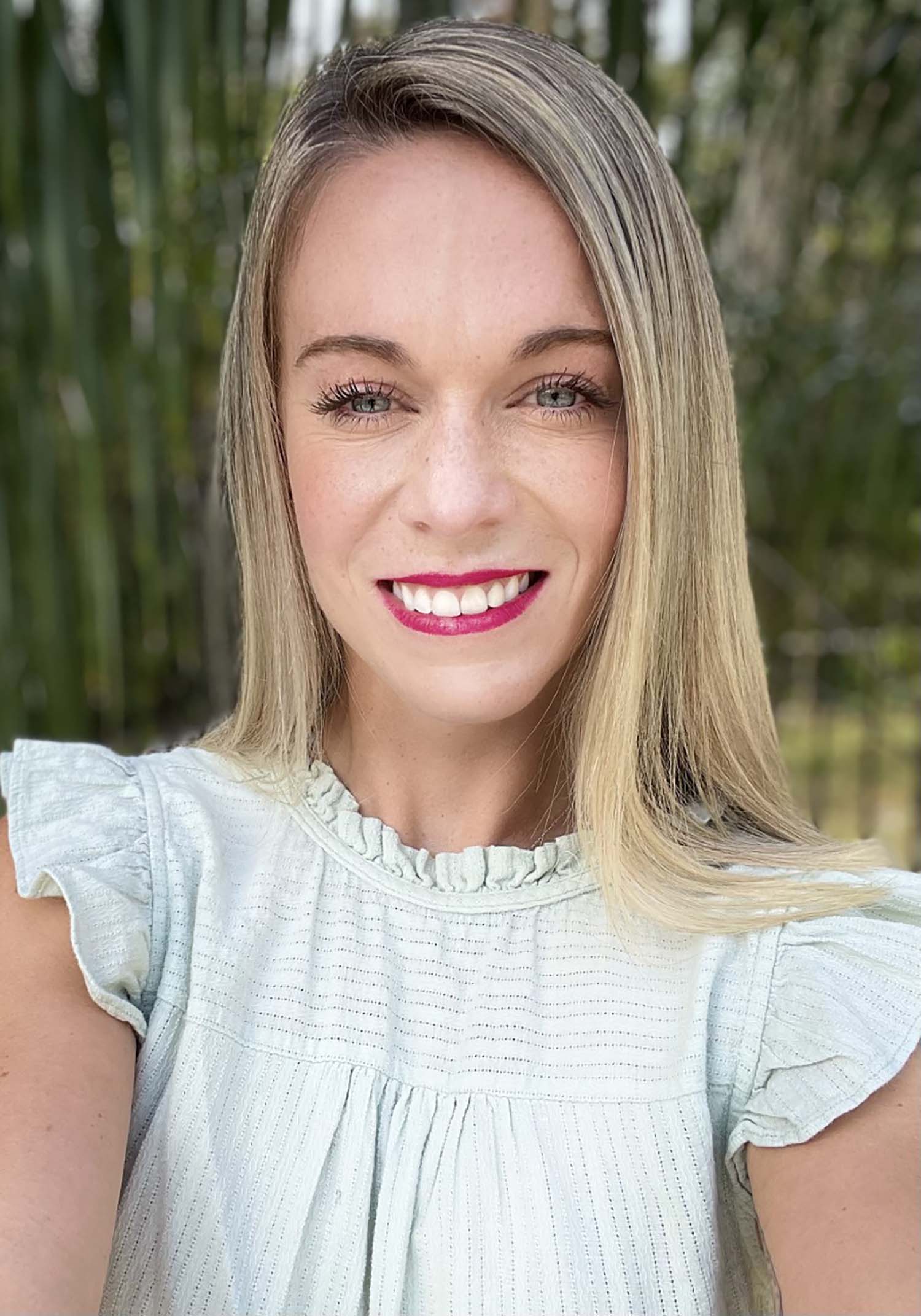 a portrait of Byrne, in which she wears a white ruffly blouse, red lipstick, and has blonde hair.