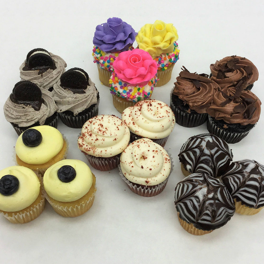 multiple groupings of cupcakes in different flavors, with colorful icing and other fun designs