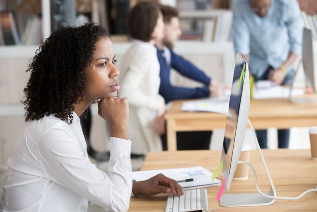 a stock photo of a serious black female employee thinking sitting in front of computer