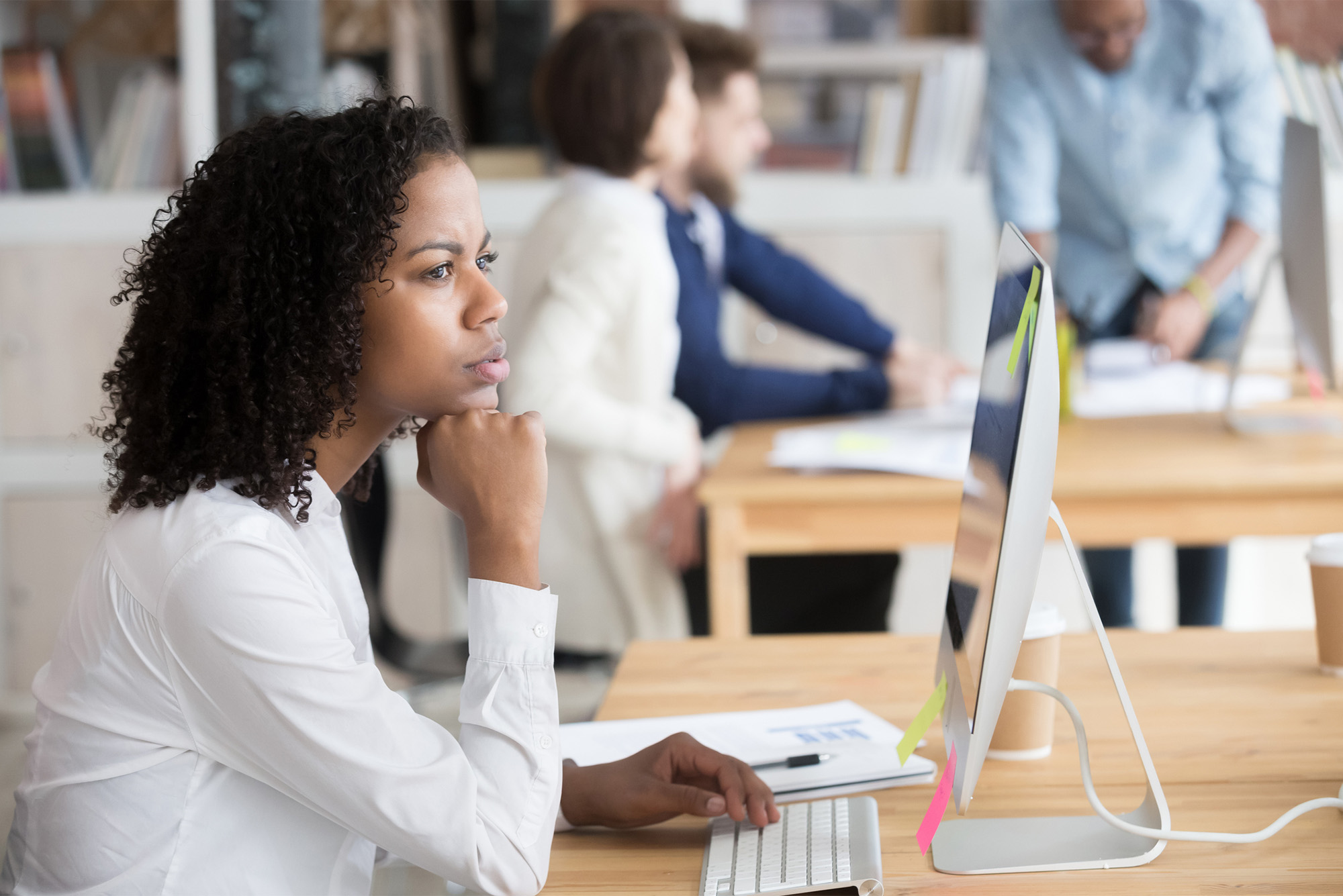 a stock photo of a serious black female employee thinking sitting in front of computer