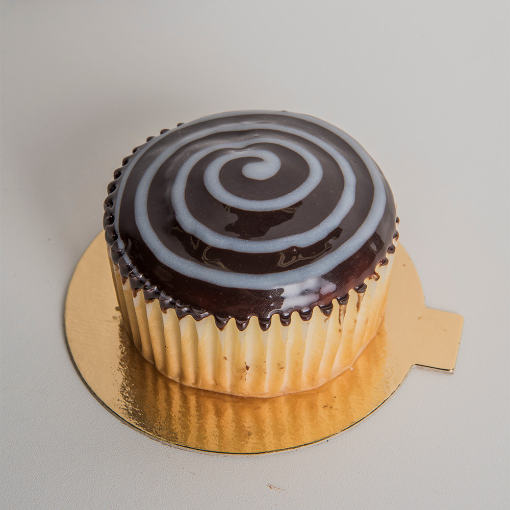 a brown cupcake with a white swirl on top of a circular golden piece of cardstock