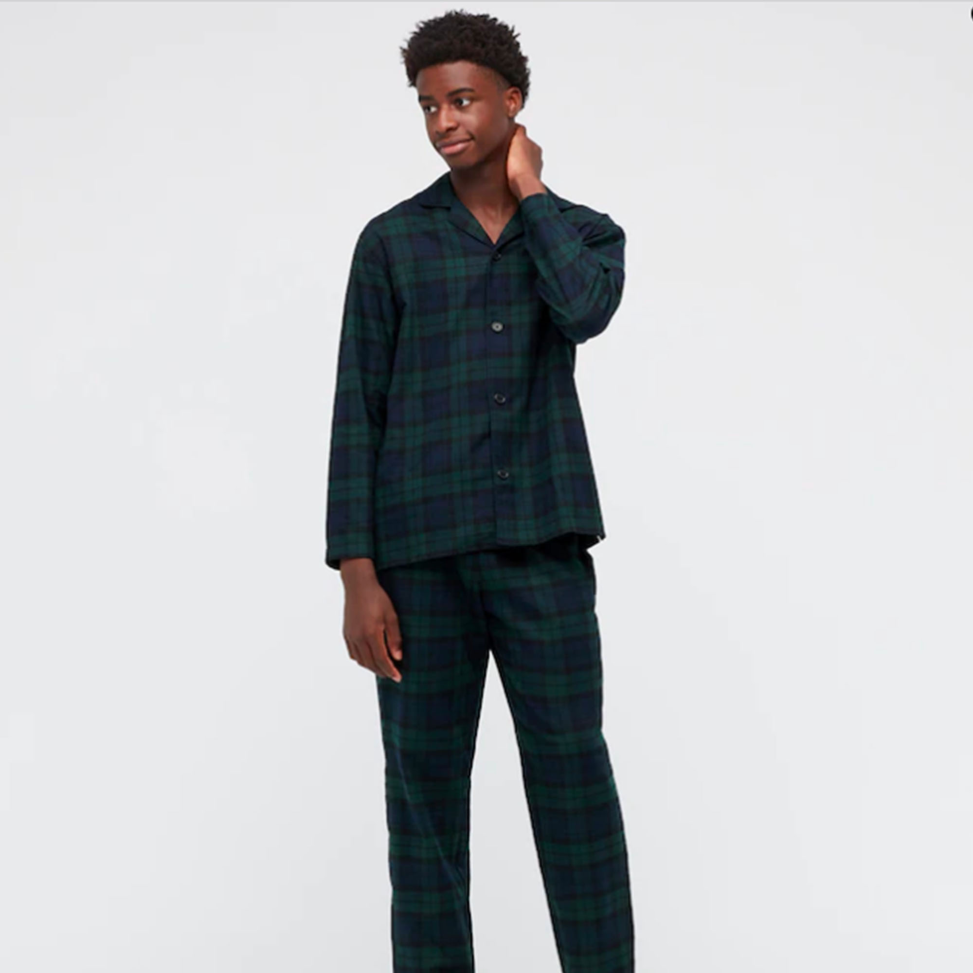 a man stands in pajamas that are dark and plaid