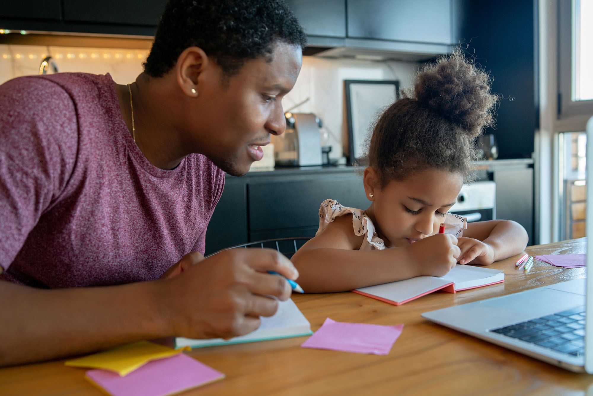 photo of a Black father helping and supporting his black daughter in their modern home