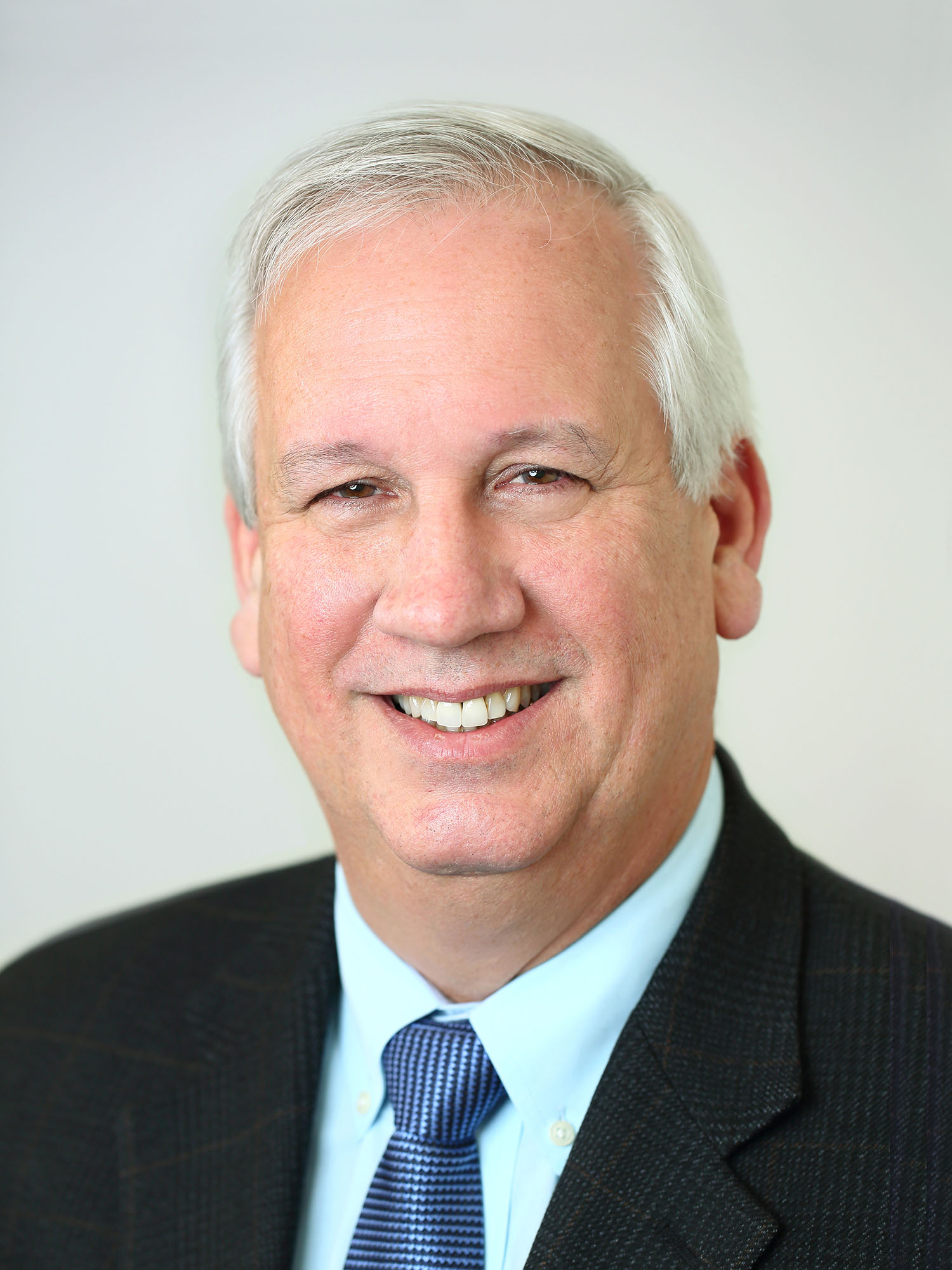 Bill Riley poses for a headshot in front of an offwhite background