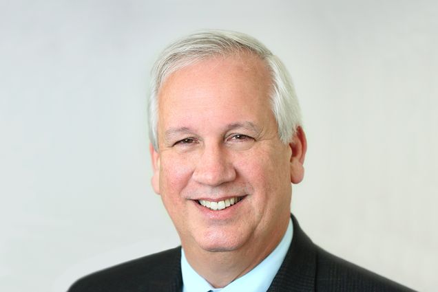 Bill Riley poses for a headshot in front of an offwhite background