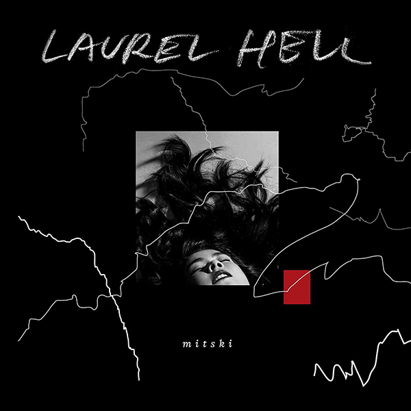Album cover of Mitski's "Laurel Hell". Cover features a black and white square image of a woman with her eyes closed and hair splayed around her as she lies on the ground. It is super-imposed on a black background with random white squiggly lightening strikes around it. The title of the album is shown in chalk-writing and the artist's name appears in a small serif-style font below the image.