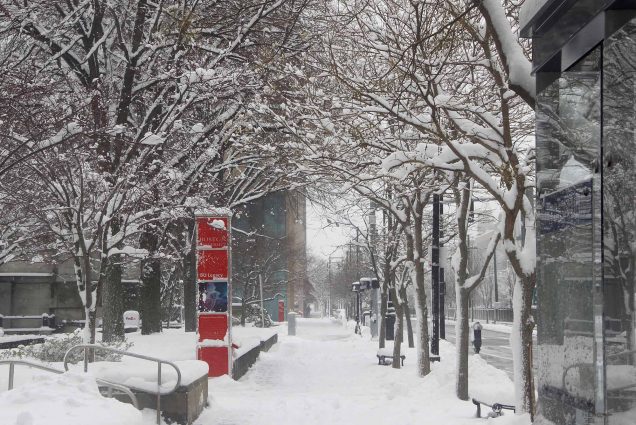 Street view photo of an empty Boston University East campus covered in snow on a snowy day.