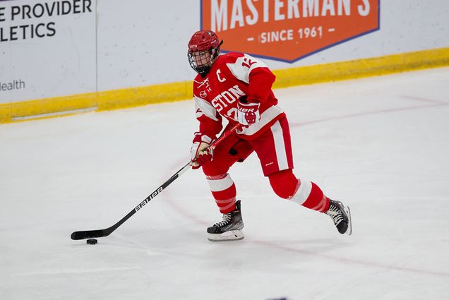 photo of photo of Kaleigh Donnelly mid-game. She wears full Boston University women's hockey gear as she skates with puck on the ice.