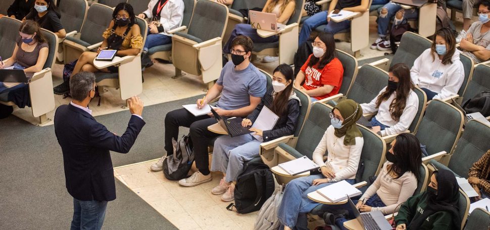 Photo of Uwe Beffert’s cell biology class September 2, 2021 in Morse Auditorium. Mask are required indoors, but distancing is not. Students sit in the rows with their notebooks open and look towards Beffert who wears a black jacket and jeans.